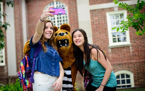 Two female college students taking a selfie with the nittany lion mascot
